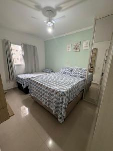a bedroom with two beds and a mirror at Apto Novo Canto do Forte in Praia Grande