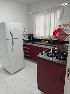 a kitchen with a white refrigerator and a stove at Apto Novo Canto do Forte in Praia Grande