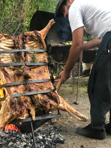 Ein Mann kocht ein Steak auf einem Grill in der Unterkunft Rio Tarde Casa Patagonica in Lago Posadas