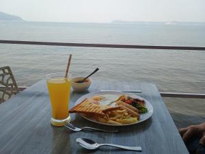 a plate of breakfast food and a glass of orange juice at GS Home on the Bay - Sea & forest view glass studio in Vagator