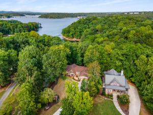 - une vue aérienne sur une maison dans les bois à côté d'un lac dans l'établissement 4bd Waterfront House in Lake Lanier with HotTub, FirePit, Wifi, Ping Pong and 2 Kaya, à Gainesville
