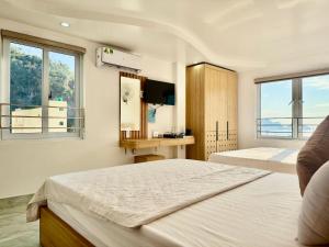 two beds in a room with two windows at Sea Dragon Hotel Cát Bà & Aparment in Cat Ba