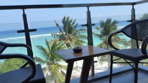 a table and chairs on a balcony with a view of the beach at Vista Beach Retreat in Hulhumale
