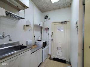 a kitchen with white cabinets and a sink and a door at avanti house大橋A3 in Shiobaru