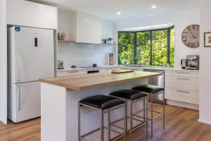 a kitchen with a white refrigerator and bar stools at Blueys Cottage in Blueys Beach +22 photos