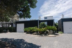 a house with two garage doors and some plants at Charming Omaha beach house in Omaha