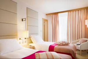 a hotel room with two beds and a chair at Sun Gardens Dubrovnik in Dubrovnik