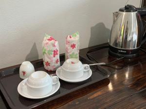 a tray with two cups and saucers and a coffee pot at Saensukkho Hotel & Resort in Chiang Rai