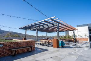 a wooden pergola with tables and benches on a patio at Modern Apartment next to Canberra Centre in Canberra