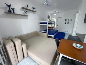 a living room with a couch and a table and a bed at Pé na Areia Praia das Toninhas - Villagio 17 in Ubatuba