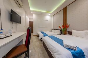 a hotel room with two beds and a tv at Hanoi Capital Hotel & Spa in Hanoi