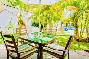 a glass table with chairs and an umbrella on a patio at Deluxe Family Comfort Balcony Room with Pool Playacar Ii in Playa del Carmen