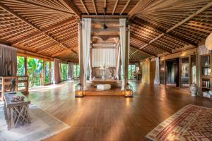 una sala de estar de planta abierta con suelo y techo de madera. en Nag Shampa Private Estate, en Payangan