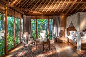 1 dormitorio con 1 cama, sillas y ventanas en Nag Shampa Private Estate, en Payangan
