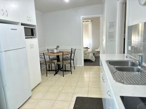 a kitchen with white appliances and a table with chairs at Serenity Holiday House Port Lincoln Holiday House in Port Lincoln +8 photos