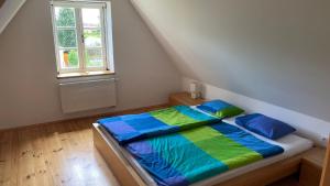 a bed with blue and green sheets in a room with a window at Cottage Faflik - Air Con And Own Sauna, Swedish house no 001 in Vlkov