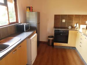a kitchen with a stainless steel refrigerator and wooden floors at Rodo2 wooden cabin Malkerns in Malkerns