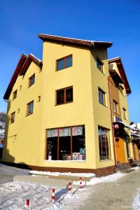 ein großes gelbes Gebäude mit Schnee davor in der Unterkunft Casa Caprioara in Petroşani