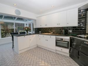 a kitchen with white cabinets and black appliances at Hazelodge in Coniston