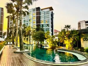 a pool in front of a building with palm trees at The private Paradise Two-bedroom condo Only women, shared accommodation in North Pattaya