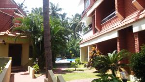 a courtyard of a building with palm trees and a pool at Hotel Thushara in Kovalam