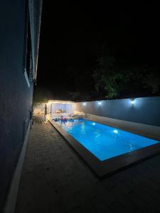a swimming pool at night with lights on a wall at Cozy House With Swimming Pool Near City Center no1 in Gabala