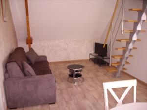 uma sala de estar com um sofá e uma escada em La Grimodière Gîte em Ranville