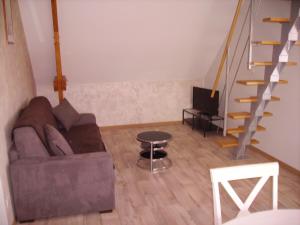 a living room with a couch and a staircase at La Grimodière Gîte in Ranville