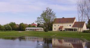 uma casa com um lago em frente a um edifício em La Grimodière Gîte em Ranville