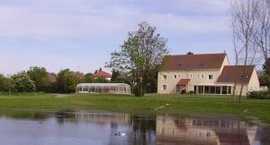 a house with a pond in front of a building at La Grimodière Gîte in Ranville