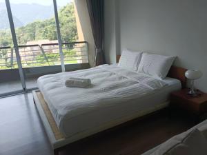 a bed in a room with a large window at La Foresta Khaoyai in Pak Chong