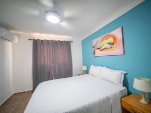 a bedroom with a white bed and a blue wall at Garden Condos 10, 2br Apt In Sosua Strip in Sosúa +7 photos