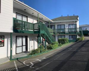 a white building with green balconies on a street at Adelaide Motel in Wellington
