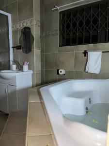 a bathroom with a bath tub and a sink at Emmanuel-Guest-House in Richards Bay