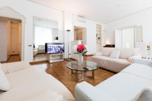 a living room with white furniture and a tv at Heart Milan Apartments Duomo Castello in Milan