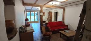 a living room with a red couch and a table at Sancier gîte au calme grand terrain circuit cascades du Hérisson in Saugeot