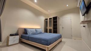 a bedroom with a bed with blue sheets and a tv at La-ngu Homie in Langu