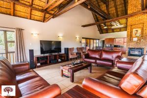 a living room with leather furniture and a flat screen tv at Zebula Golf and Wildlife Estate - Spectacular View Pax 13 - Moi Signature Luxury villa in Mabula