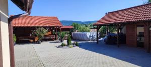 a patio with two pavilions with benches and trees at Farkaslaki Panoráma Vendégház in Lupeni