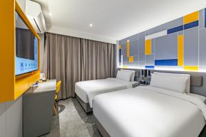 a hotel room with two beds and a tv at 7Days Inn Xi'an East Street in Xi'an