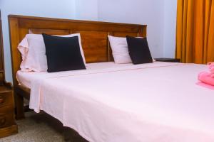 a bedroom with a large white bed with black and white pillows at Mirissa Turtle Point Guest in Mirissa