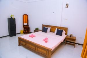 a bedroom with a bed with pink slippers on it at Mirissa Turtle Point Guest in Mirissa