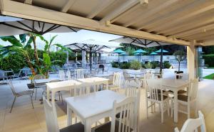 a restaurant with white tables and chairs and umbrellas at Hotel Korali in Troulos