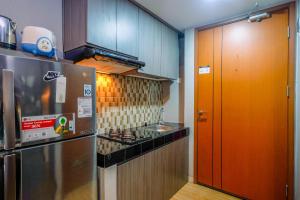une cuisine avec une cuisinière et un réfrigérateur dans l'établissement Cozy Living and Homey Studio Apartment at Margonda Residence 5 By Travelio, à Depok