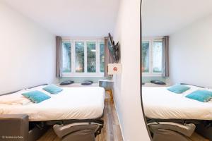 deux lits dans une chambre avec un miroir dans l'établissement Studio Moderne au coeur de Paris, à Paris
