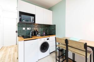 une cuisine avec des armoires blanches et une laveuse et une sécheuse dans l'établissement Studio Moderne au coeur de Paris, à Paris