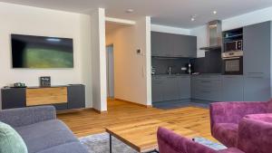 een woonkamer met 2 paarse banken en een keuken bij Moselhaus Krieger in Traben-Trarbach