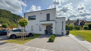 een wit huis met een auto ervoor geparkeerd bij Moselhaus Krieger in Traben-Trarbach