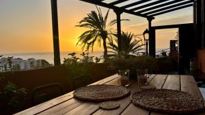 a wooden table with two plates on it with a view of the ocean at Casa Moni con Vistas al Mar in Playa de Santiago