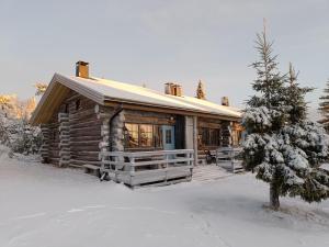Una cabaña de troncos en la nieve con un árbol al frente. en Huipuntupa B7, en Syöte